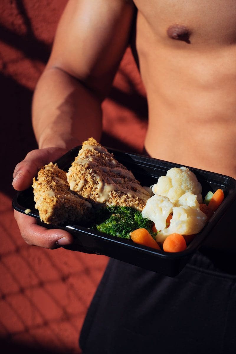 person holding cooked food on black factor 75 tray